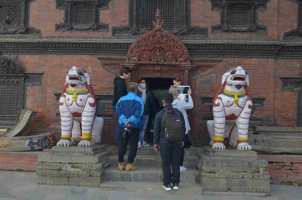 Tourists viewing the entrance to a traditional Newari brick temple in Patan Durbar Square